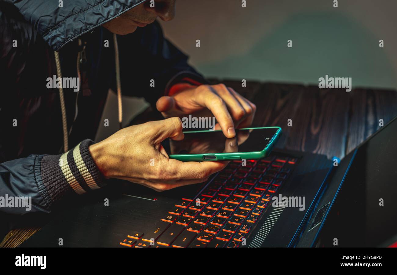 Hacker Video Two Keyboards A hacker with a phone is typing with his hands on a laptop keyboard in ...