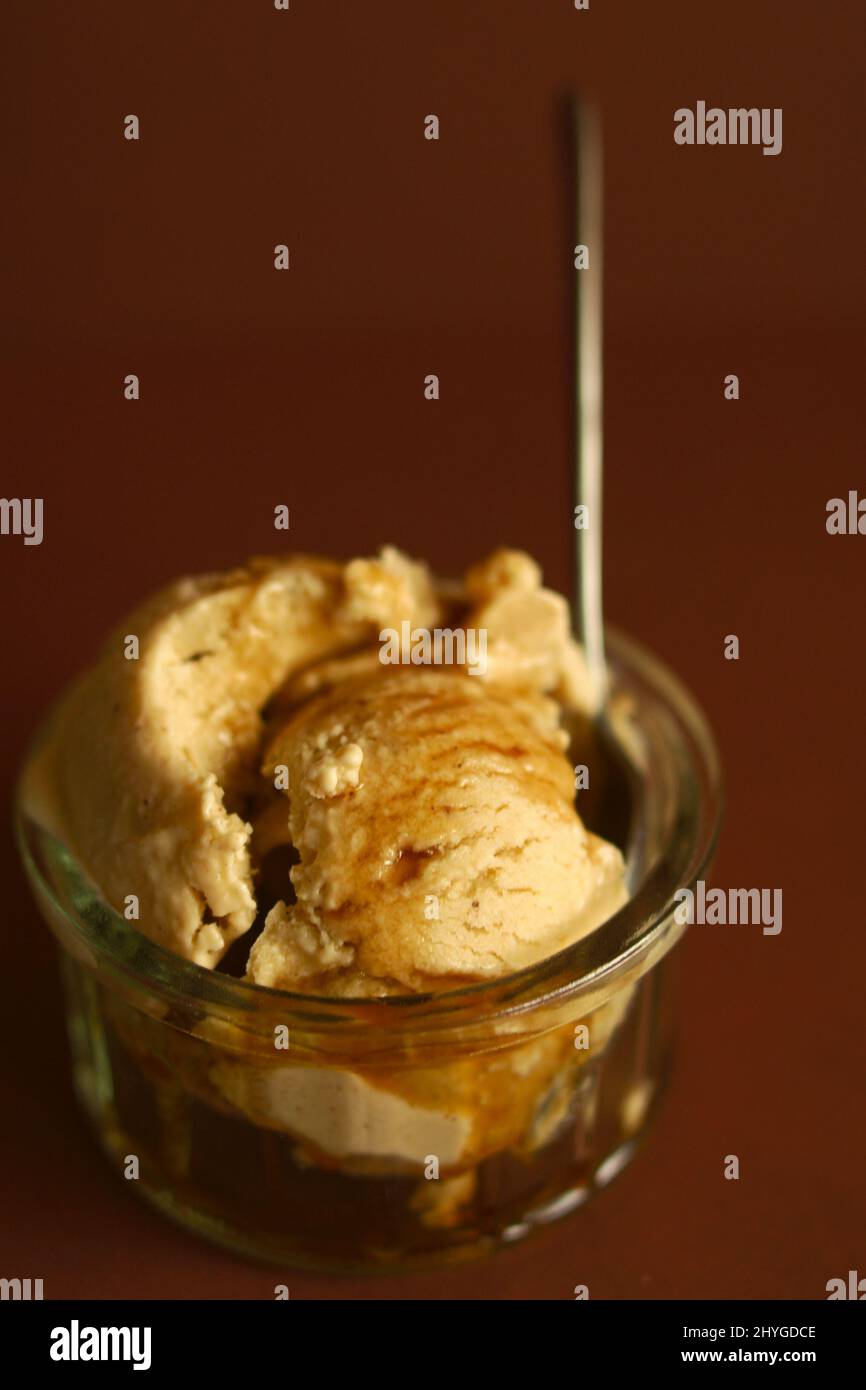 Serving of cinnamon ice cream with maple syrup isolated on a brown