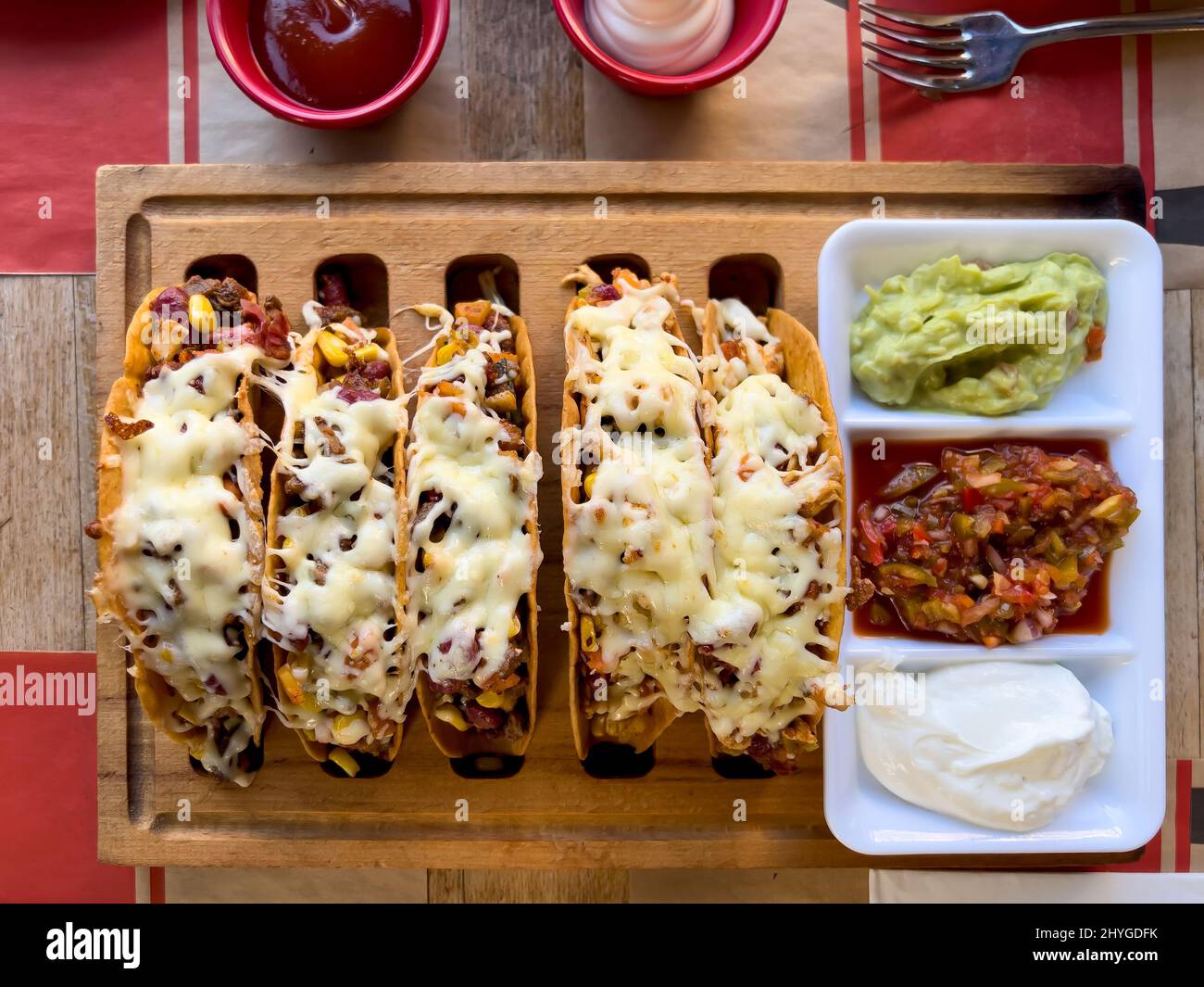 Chicken and cheddar cheese tacos on a taco board with sauces on the side Stock Photo Alamy
