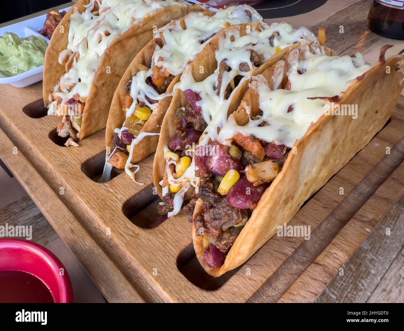 Chicken and cheddar cheese tacos on a taco board with sauces on the