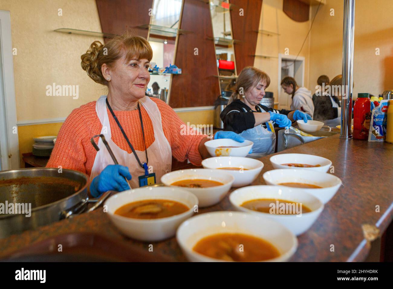 UZHHOROD, UKRAINE - MARCH 14, 2022 - A volunteer arranges the bowls of soup on a counter in a restaurant that offers free meals to internally displace Stock Photo