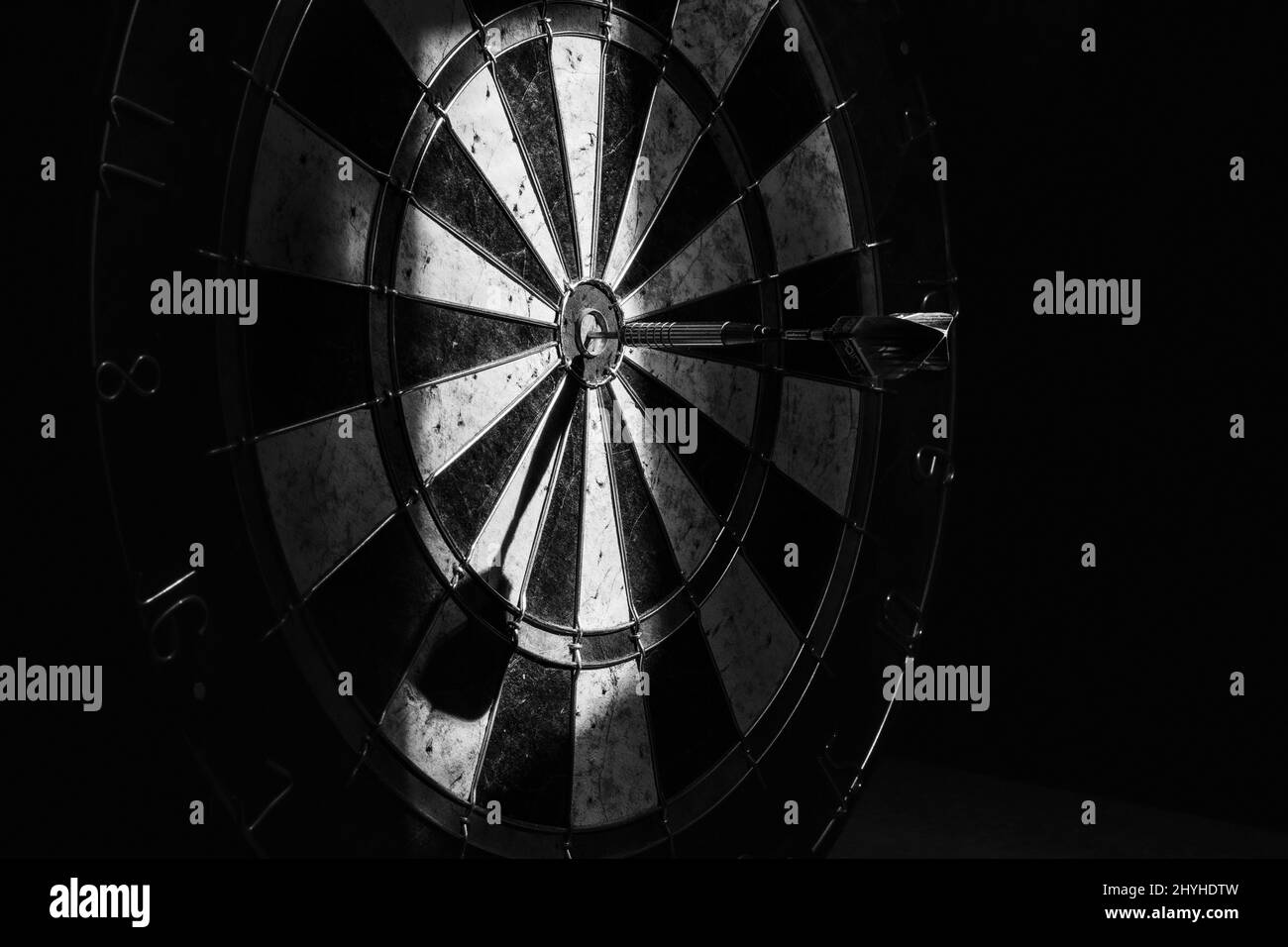 Closeup of a darts board with a dart hits the target, shot in grayscale - concept of success Stock Photo