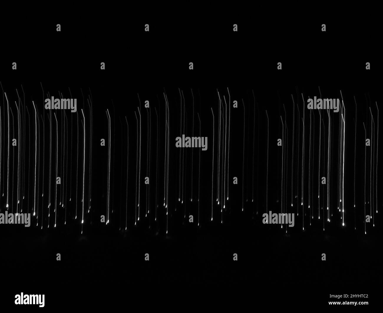 Abstract falling lines background. Many white lights going down on black background representing the concept of fall Stock Photo