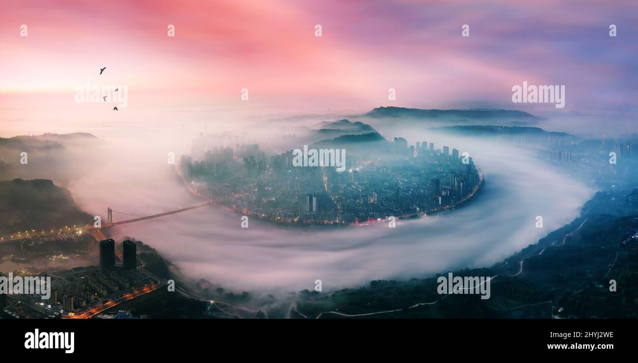 Chongqing, Chongqing, China. 15th Mar, 2022. On March 15, 2022, Jiangjin, Chongqing, affected by the recent warming weather, is now a spectacle of advective fog. The whole city is shrouded in clouds and fog, like a fairyland on earth. Overlooking in the morning light, the Yangtze River and the whole city are shrouded in rising clouds and mists. High-rise buildings, the Yangtze River Bridge, and Binjiang Road are looming in the sea of fog, forming magnificent landscapes, like a fairyland on earth.Advection fog is a unique landscape formed by the condensation of water vapor when the temperatur Stock Photo
