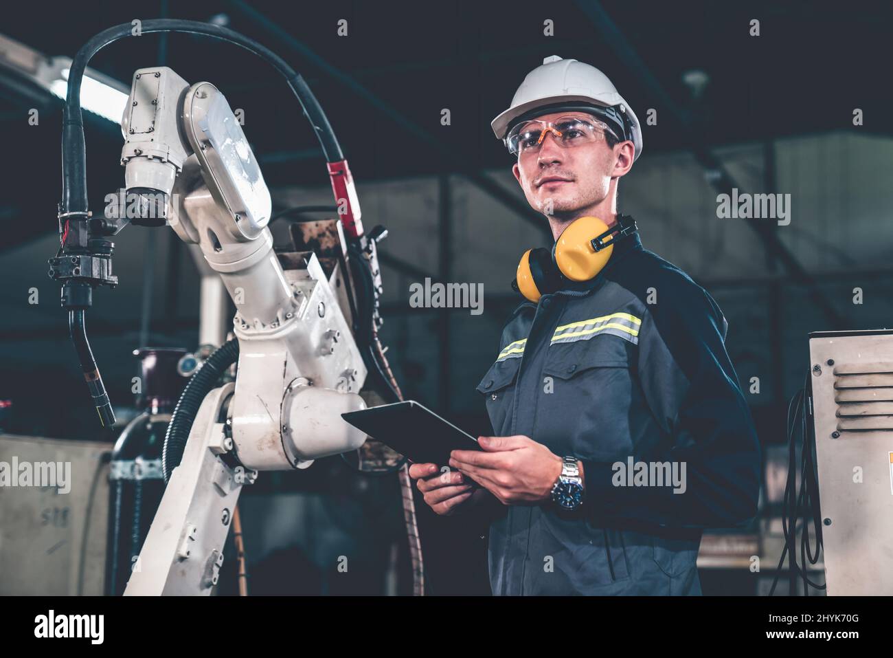 Young factory worker working with adept robotic arm in a