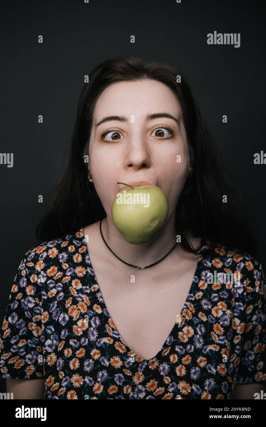 girl close up biting apple on dark bacground like Magriite painting