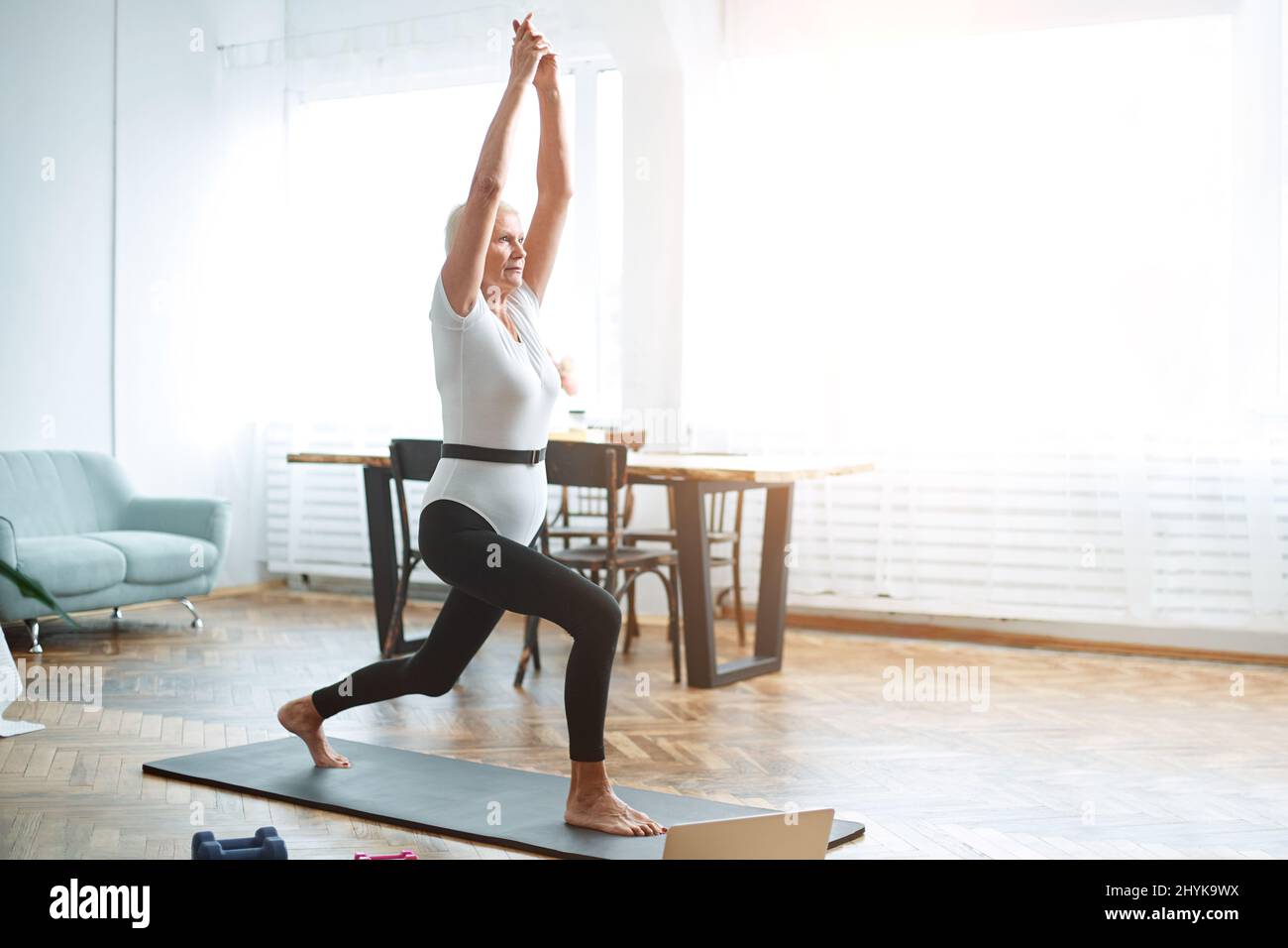 elderly woman sitting in a yoga pose in front of an open laptop Stock ...
