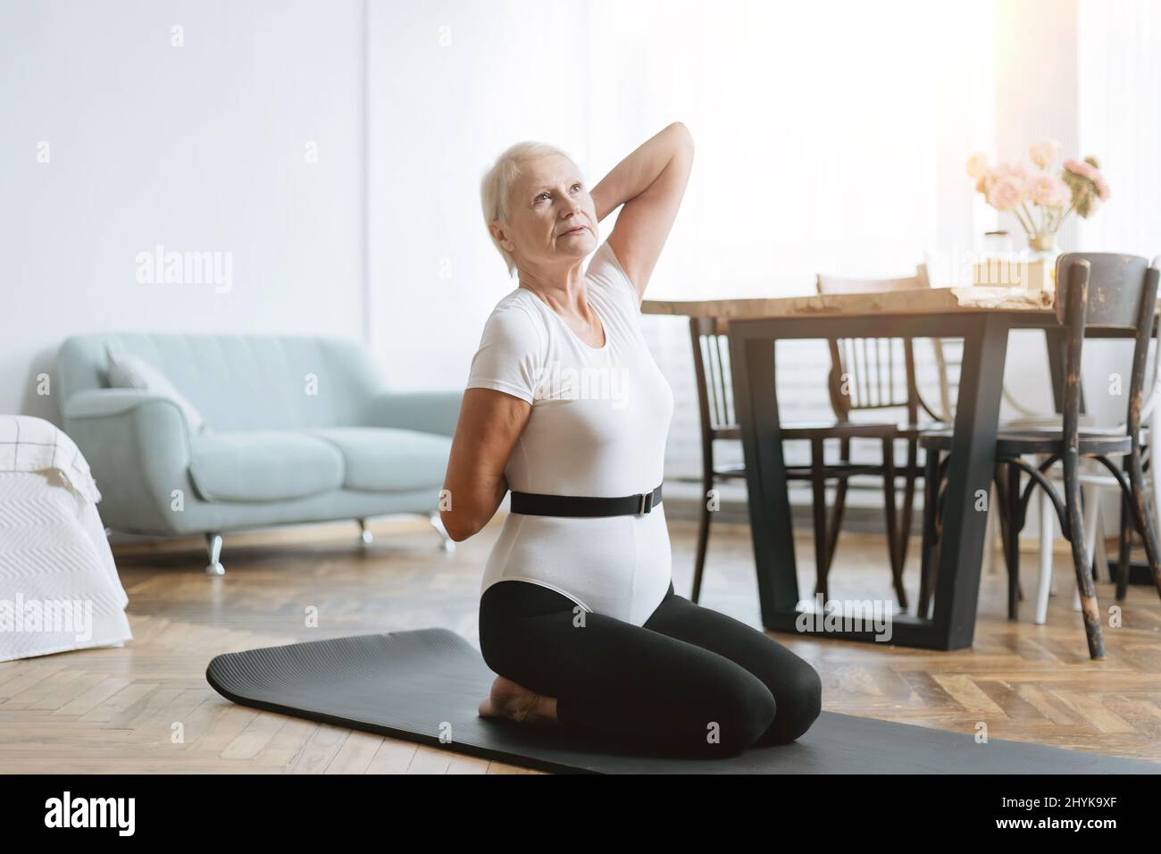 elderly woman sitting in a yoga pose in front of an open laptop Stock ...
