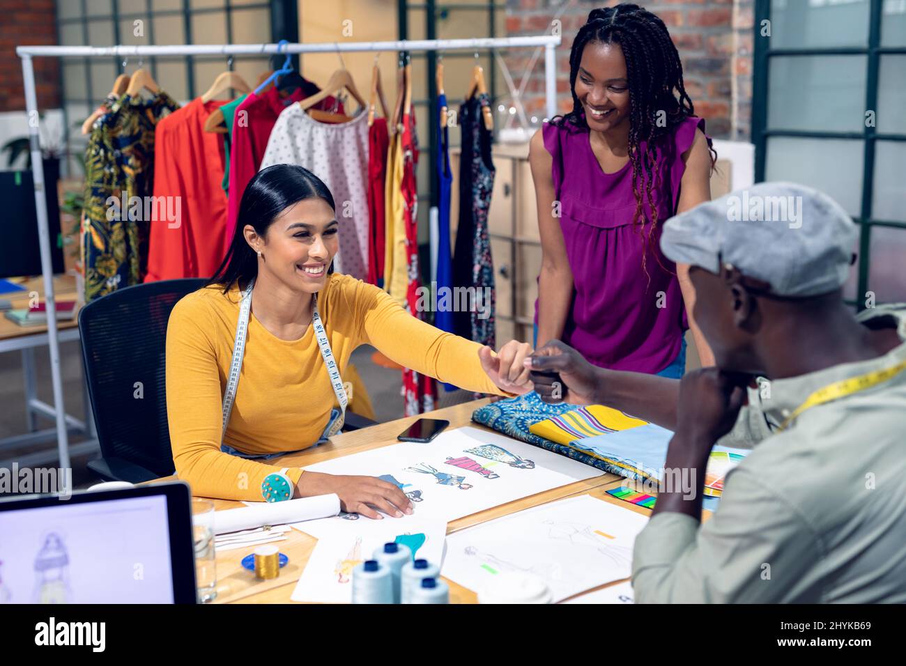 African american young female designer looking multiracial young male, female workers doing fistbump Stock Photo