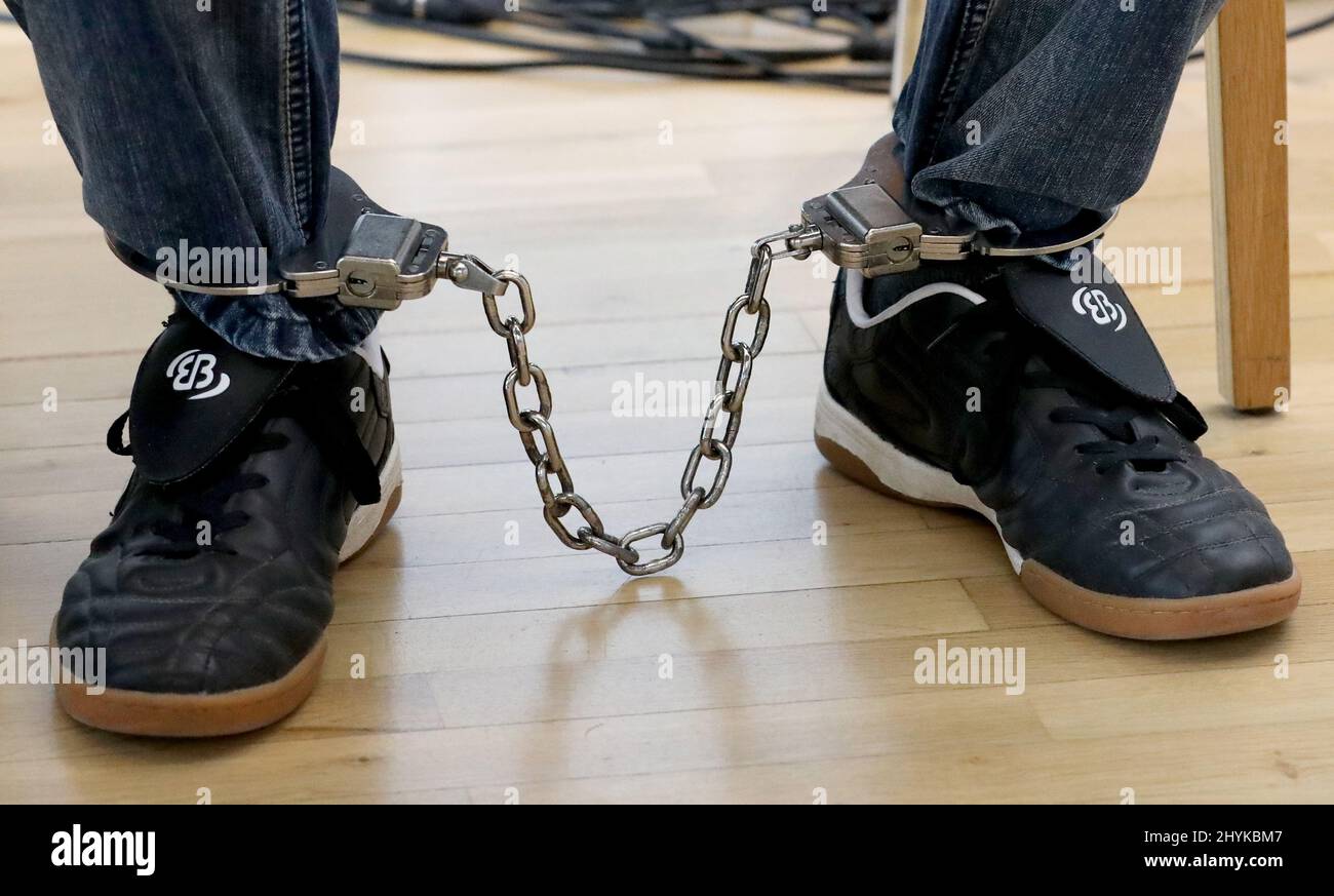 15 March 2022, Mecklenburg-Western Pomerania, Neubrandenburg: The defendant in the trial for attempted murder sits with an ankle bracelet in the hall of the regional court and waits for the trial to begin. According to the prosecution, the 56-year-old is alleged to have choked a 33-year-old woman to unconsciousness, doused her with a flammable liquid and set her on fire in October 2021 in a dispute over paternity for a baby, among other things. Photo: Bernd Wüstneck/dpa-Zentralbild/dpa Stock Photo