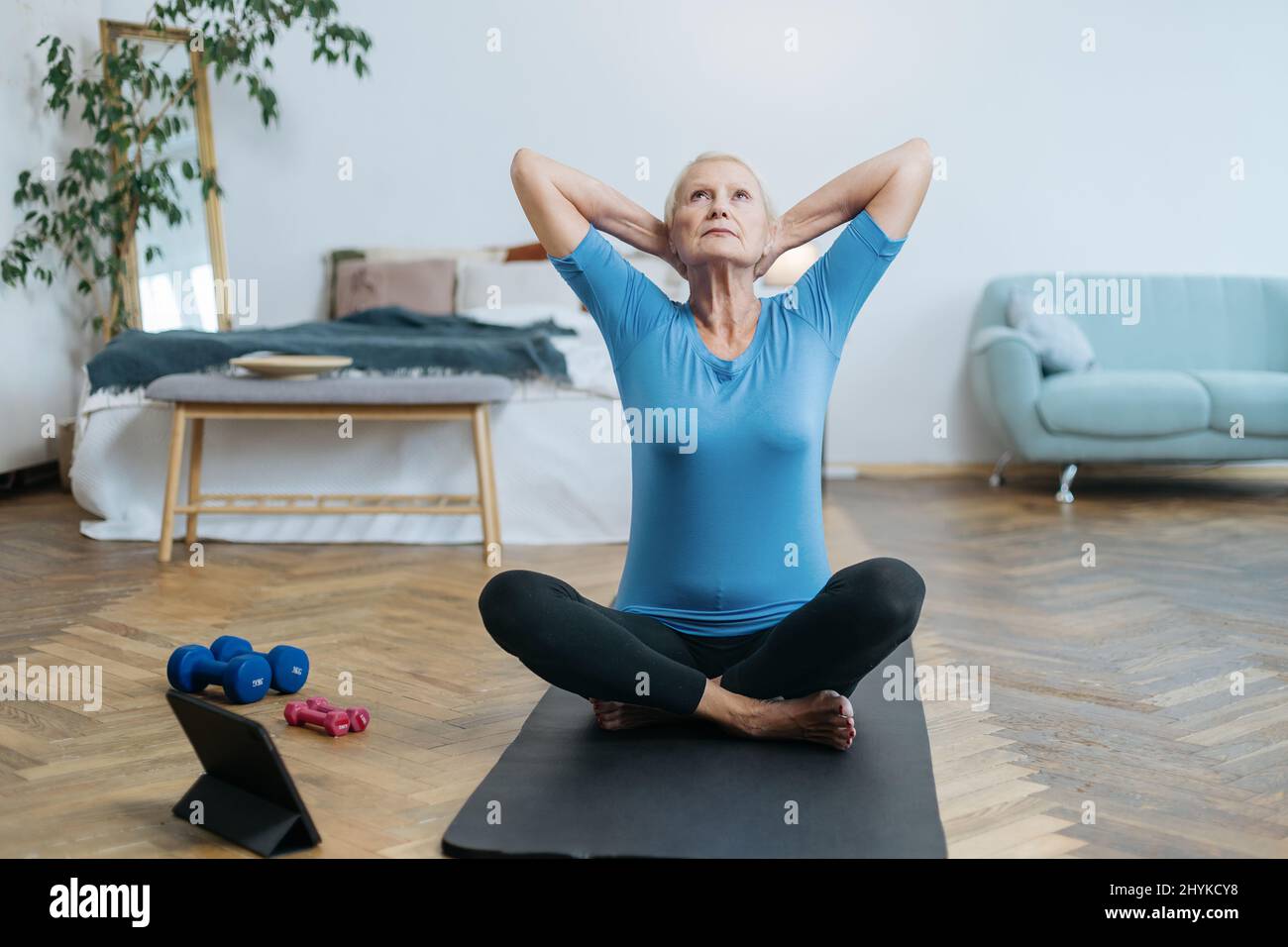 elderly woman sitting in a yoga pose in front of an open laptop Stock ...