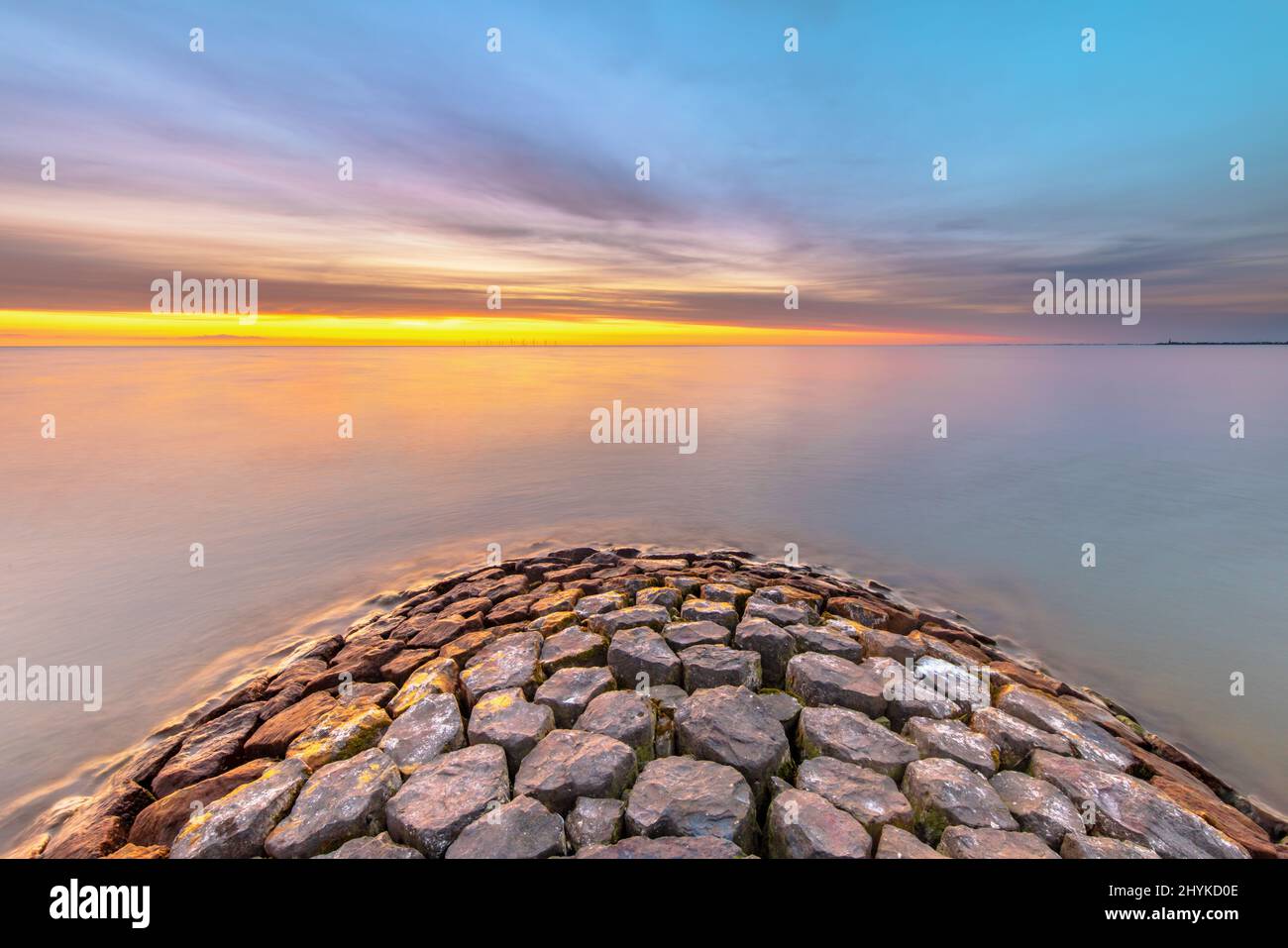 Typical basalt breakwater pier construction at  IJsselmeer near the town of Hindeloopen in the Friesland Province at sunset, Netherlands. Stock Photo