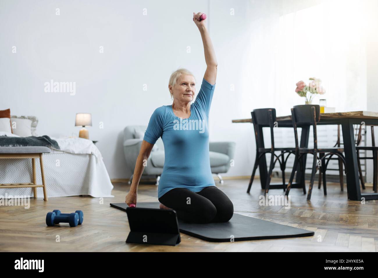 elderly woman sitting in a yoga pose in front of an open laptop Stock ...