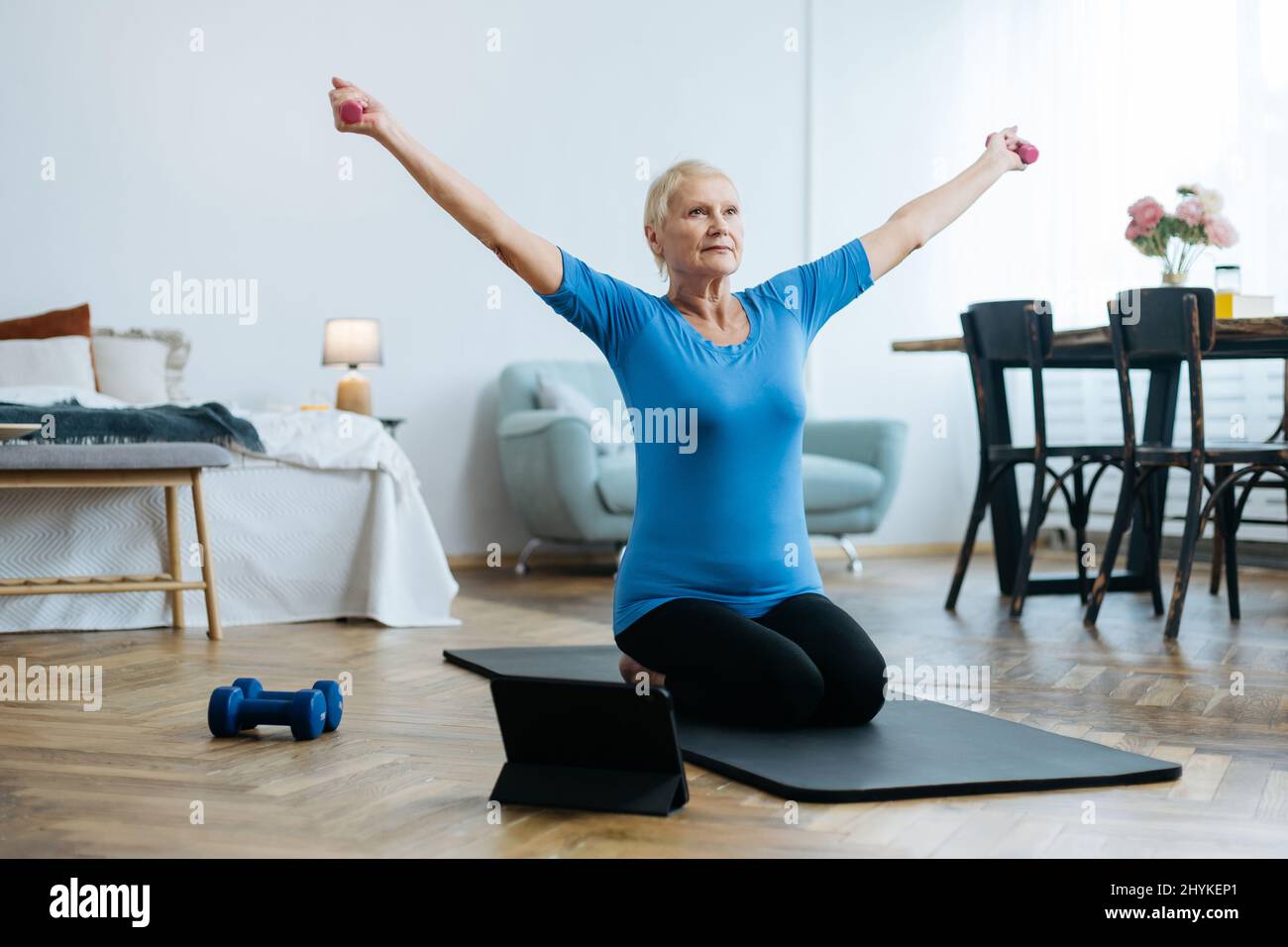 elderly woman sitting in a yoga pose in front of an open laptop Stock ...