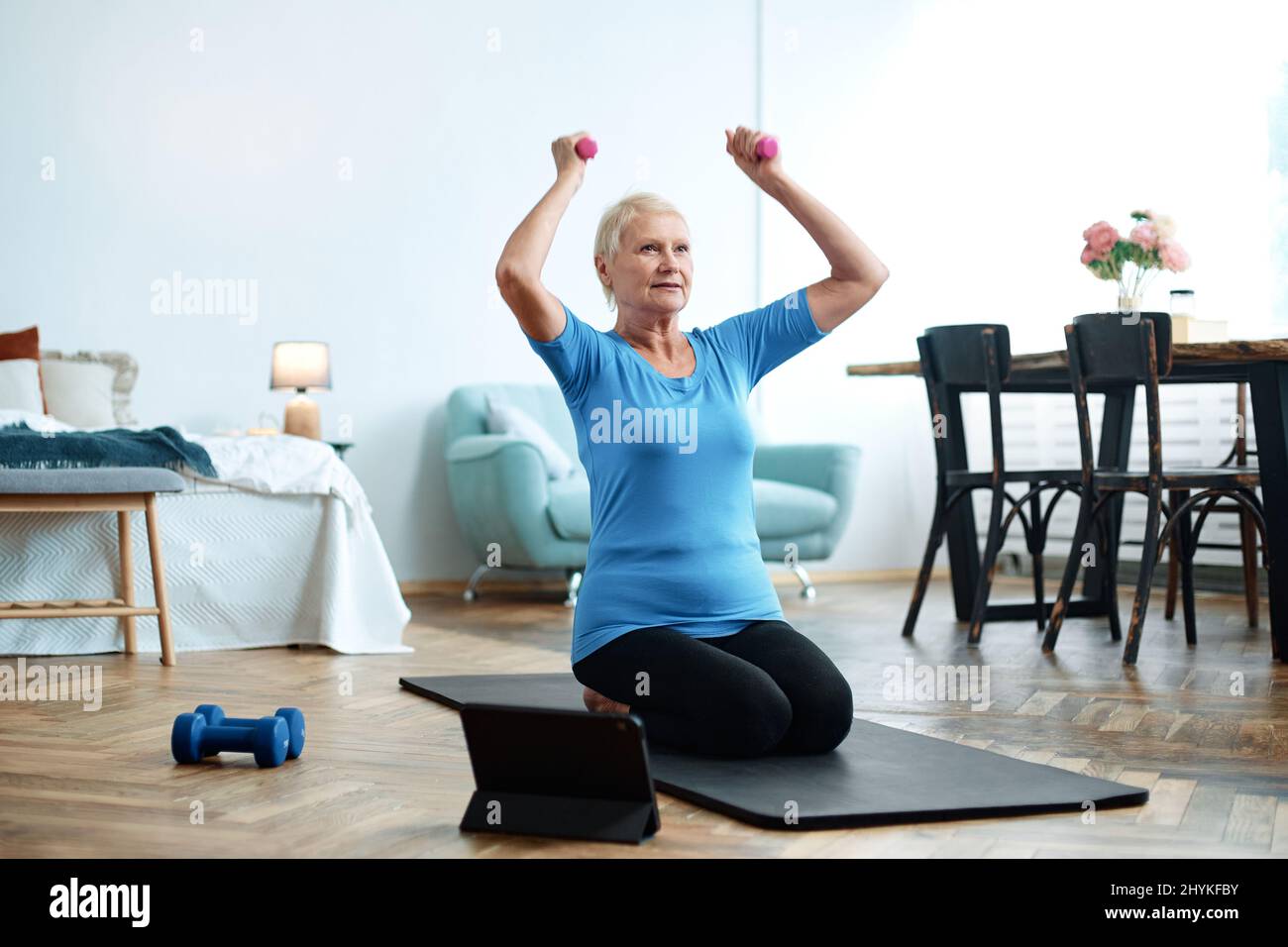 elderly woman sitting in a yoga pose in front of an open laptop Stock ...