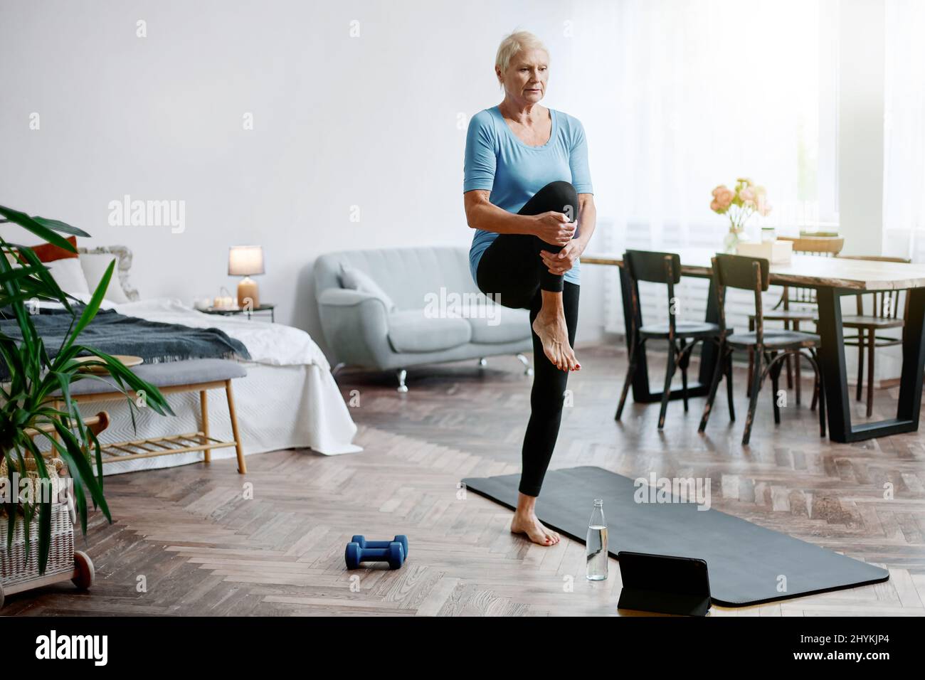 elderly woman sitting in a yoga pose in front of an open laptop Stock ...