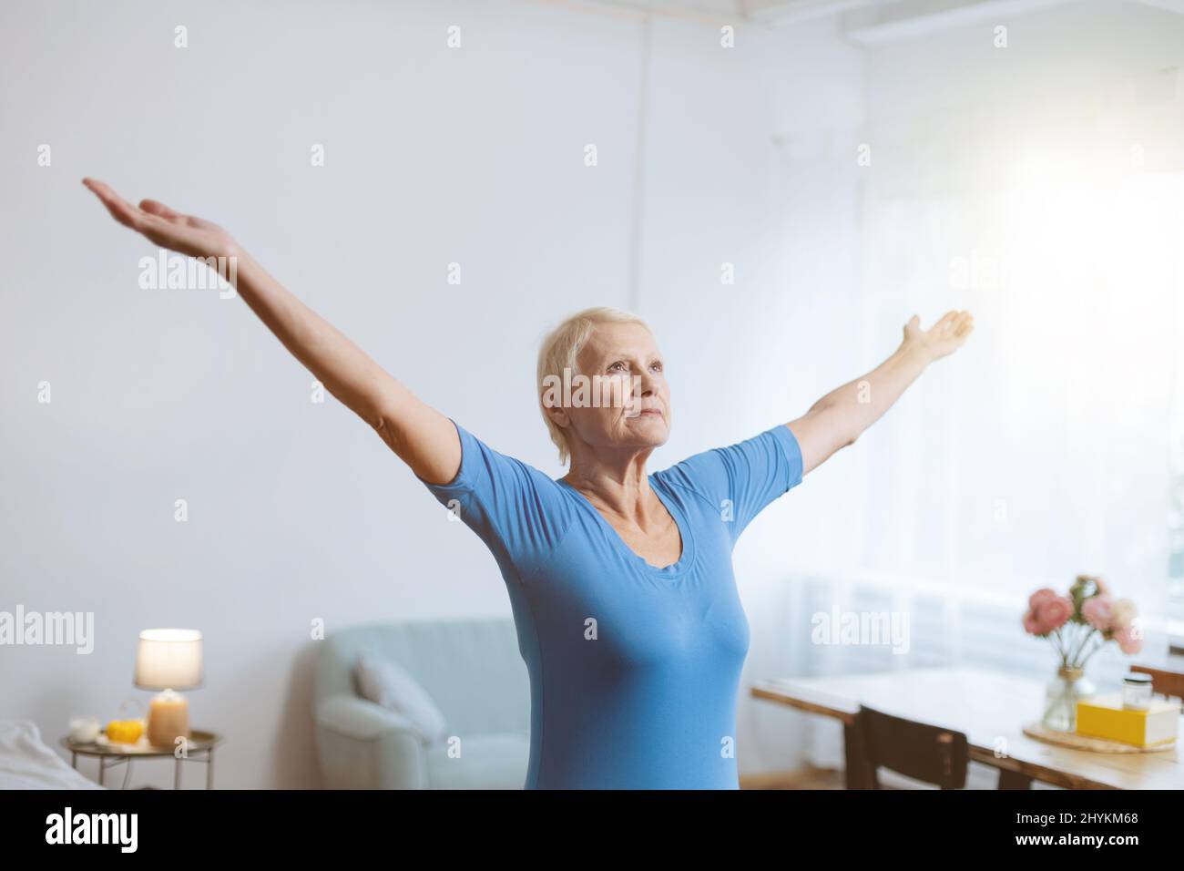 elderly woman sitting in a yoga pose in front of an open laptop Stock ...