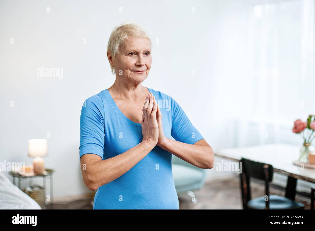 elderly woman sitting in a yoga pose in front of an open laptop Stock ...