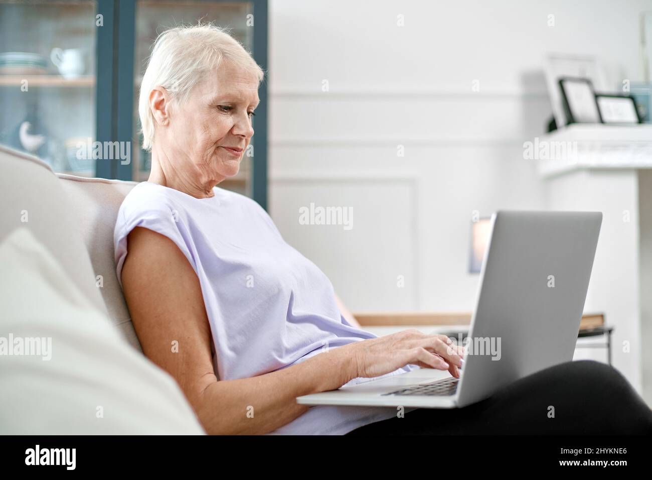 elderly woman sitting in a yoga pose in front of an open laptop Stock ...