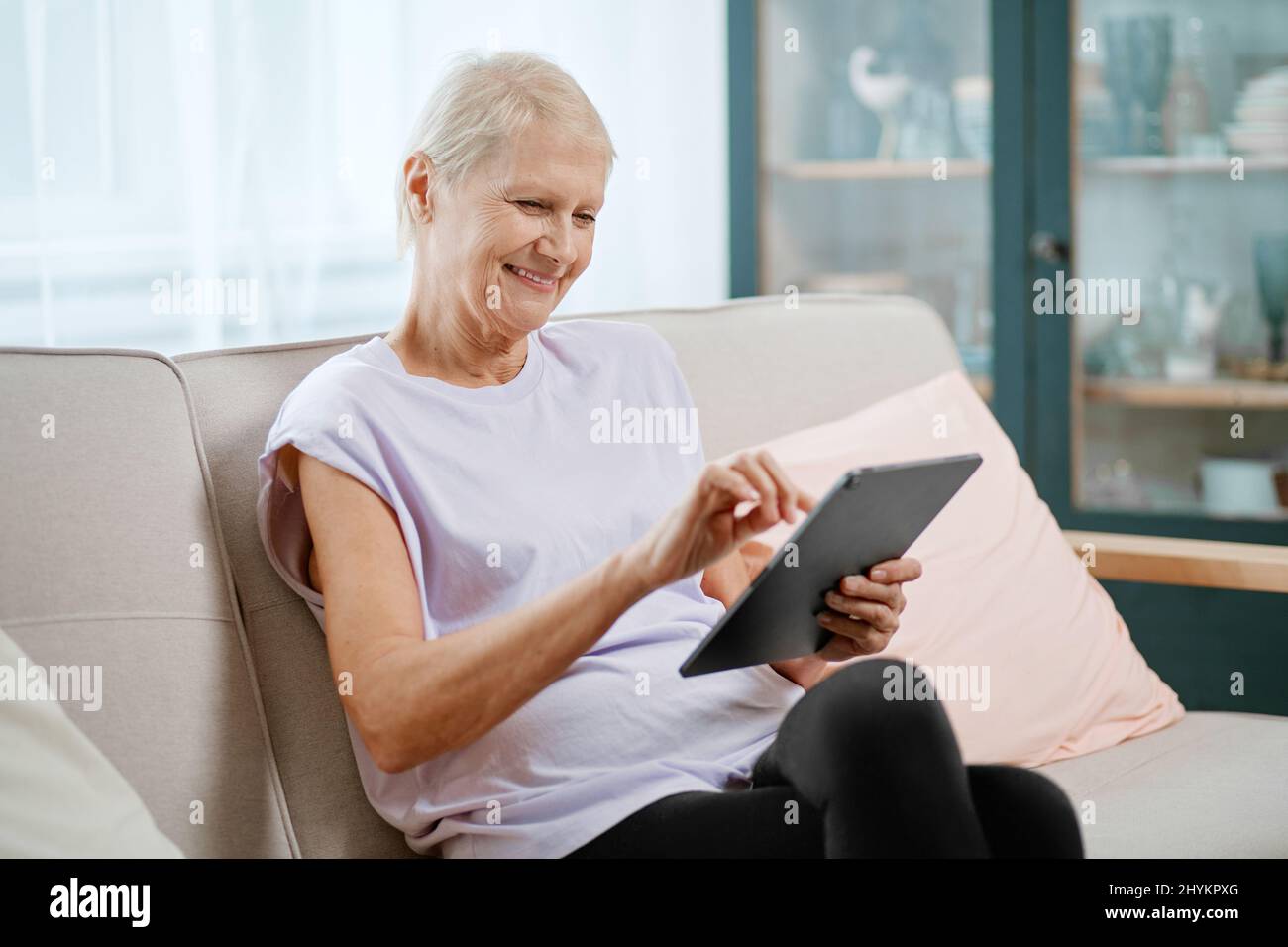 elderly woman sitting in a yoga pose in front of an open laptop Stock ...