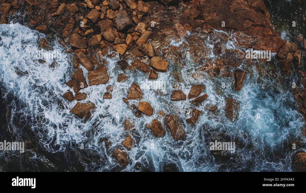 Bird's eye view of the ocean waves hitting the rocky shore Stock Photo ...