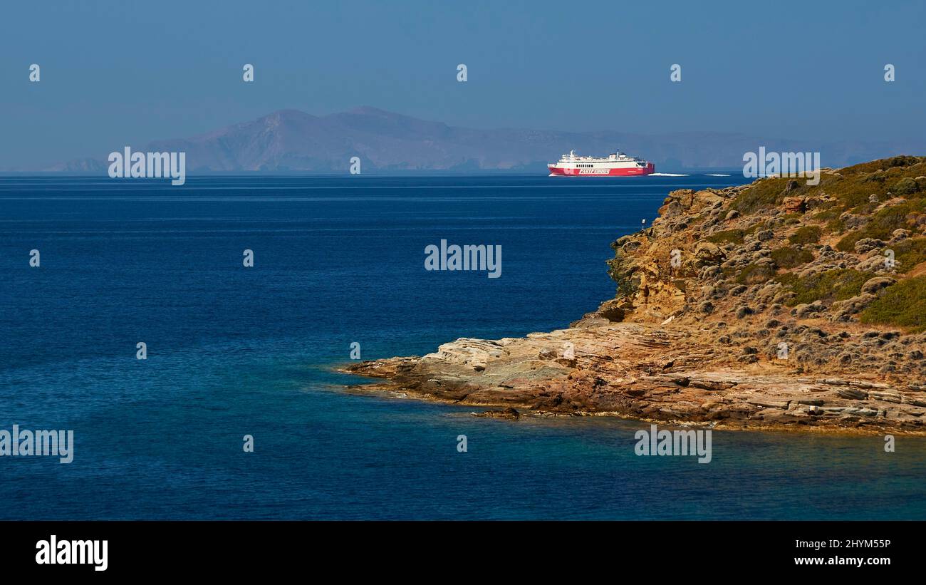 Car ferry, fast ferries, goes from right to left, rocky coast, sea turquoise and blue, sky cloudless and blue, Batsi, Andros Island, Cyclades, Greece Stock Photo