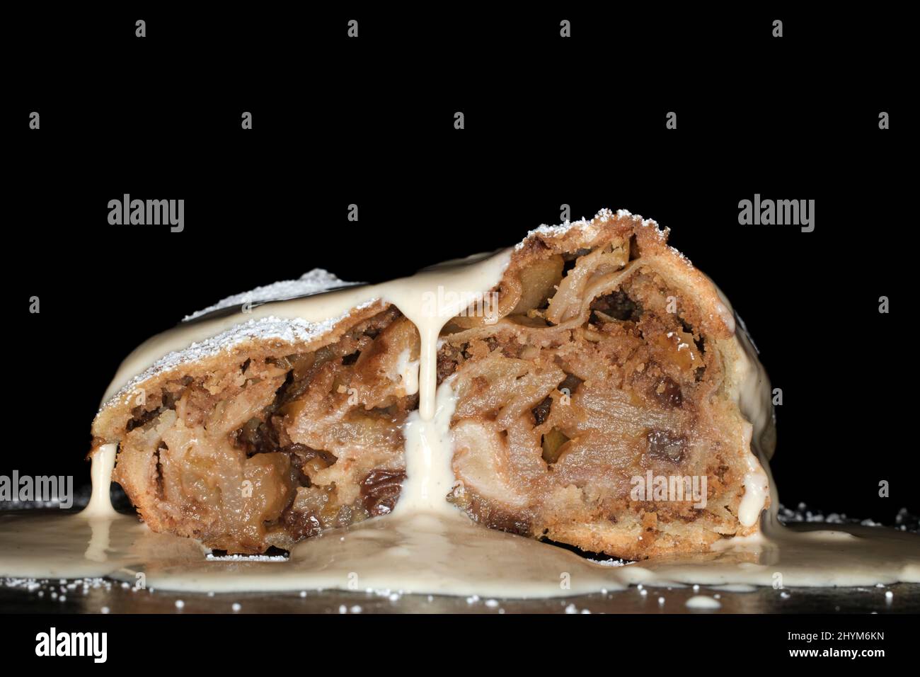 Apple strudel with sultanas, vanilla sauce and icing sugar, studio photography with black background Stock Photo