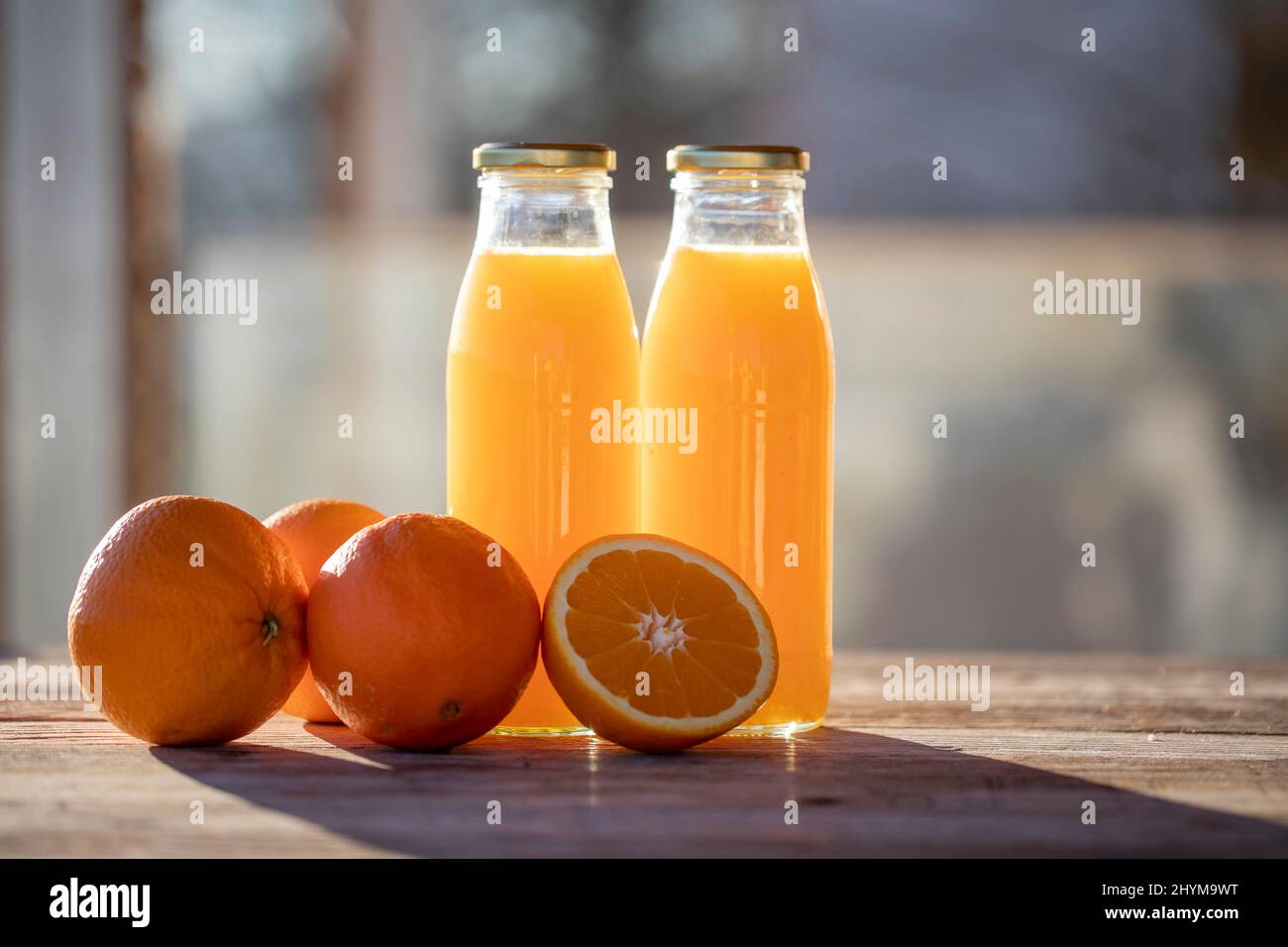 https://c8.alamy.com/comp/2HYM9WT/orange-juice-organic-homemade-freshly-squeezed-in-bottle-next-to-oranges-in-the-morning-sun-2HYM9WT.jpg