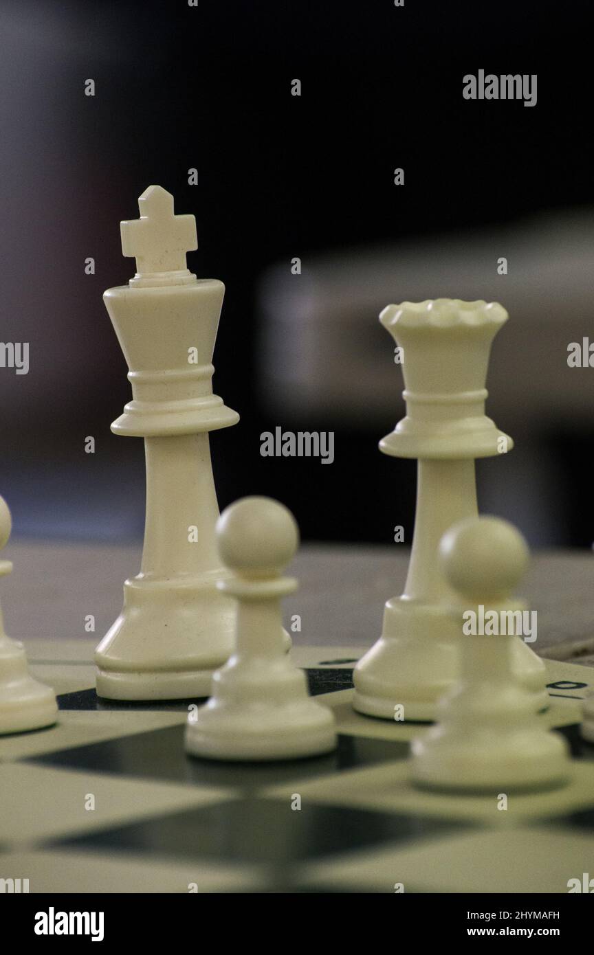 Close-up photo of chess pieces on a chess board with a beautiful blurry background. Pieces here are king, queen, pawns, a night, rook and a bishop. Stock Photo