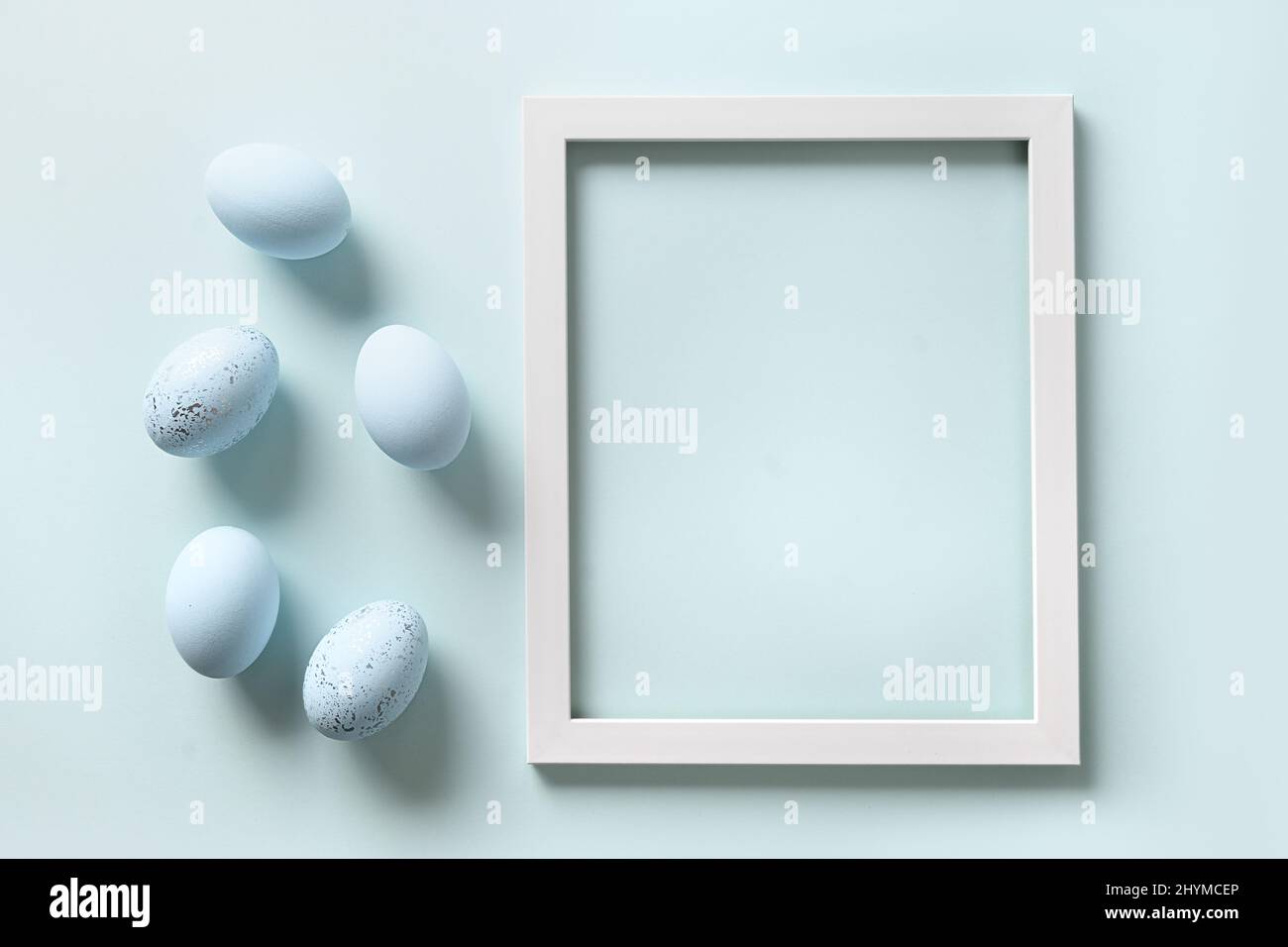 Easter frame with blue eggs on blue background. Spring monochrome greeting card with copy space. Top view. Stock Photo