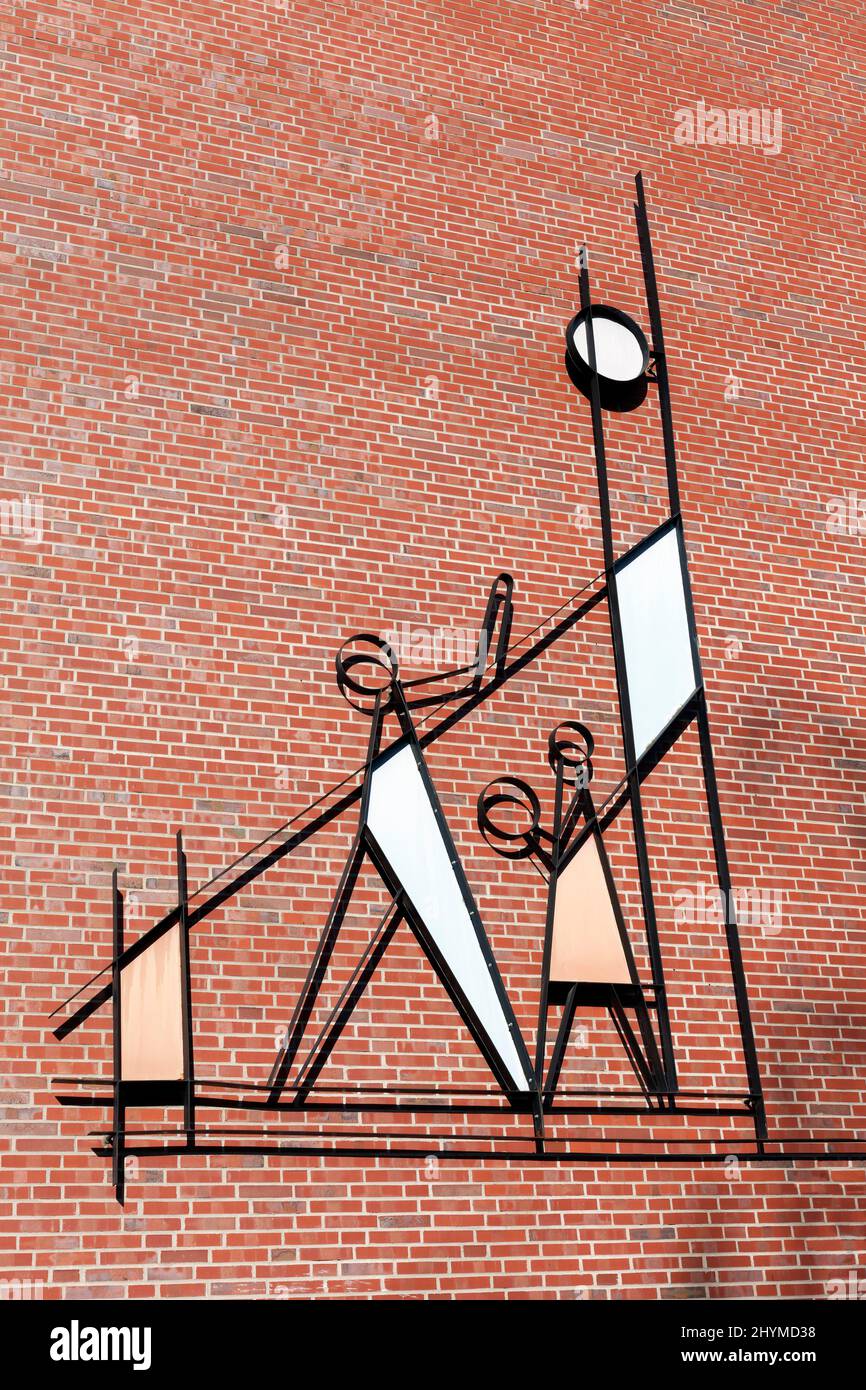 Adult and child playing ball, abstract metal figures on the brick facade of a housing estate, Duesseldorf, North Rhine-Westphalia, Germany Stock Photo