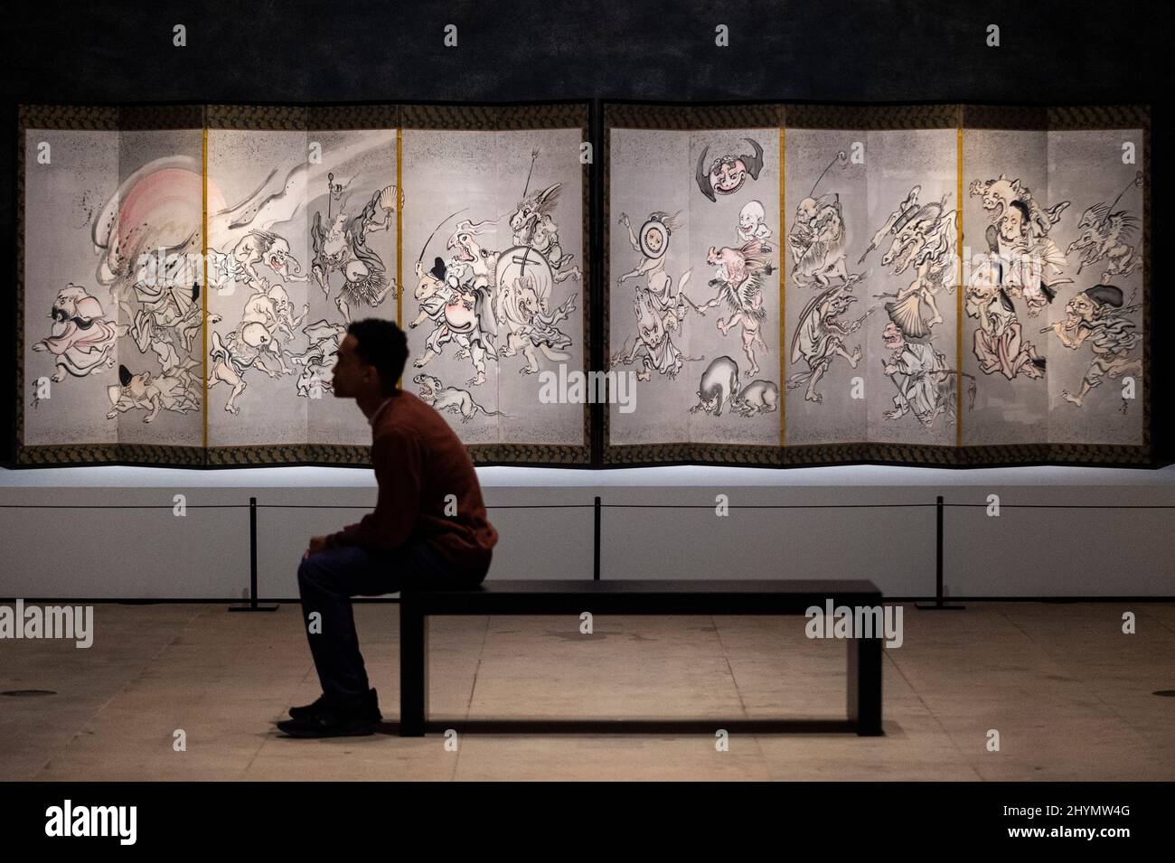 London, UK.  15 March 2022. A staff member views 'Night Procession of One Hundred Demons', 1871/89, by Kawanabe Kyōsai. Preview of Kyōsai: The Israel Goldman Collection exhibition at the Royal Academy of Arts where 80 works by late 19th century Japanese painter Kawanabe Kyōsai are on display 19 March to 19 June 2022 in the artist’s first solo UK exhibition in 30 years.  Credit: Stephen Chung / Alamy Live News Stock Photo
