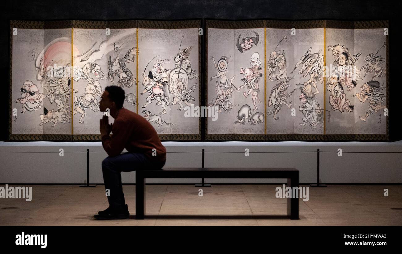 London, UK.  15 March 2022. A staff member views 'Night Procession of One Hundred Demons', 1871/89, by Kawanabe Kyōsai. Preview of Kyōsai: The Israel Goldman Collection exhibition at the Royal Academy of Arts where 80 works by late 19th century Japanese painter Kawanabe Kyōsai are on display 19 March to 19 June 2022 in the artist’s first solo UK exhibition in 30 years.  Credit: Stephen Chung / Alamy Live News Stock Photo