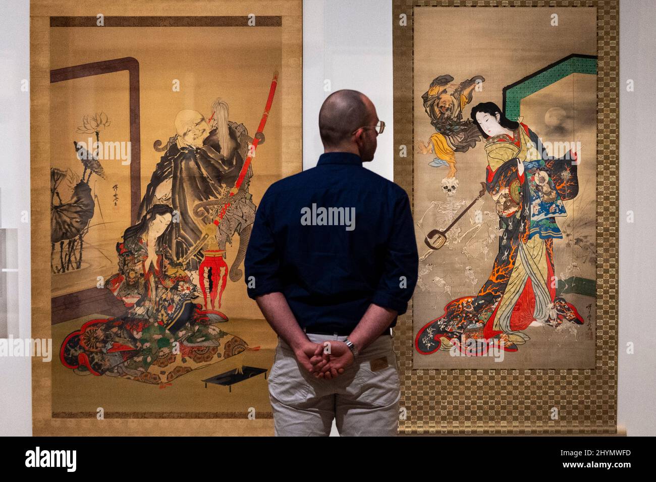 London, UK.  15 March 2022. A staff member views (L) 'Hell Courtesan and Ikkyu' and 'Hell Courtesan, Dancing Ikkyu and Skeletons', both 1871/89, by Kawanabe Kyōsai. Preview of Kyōsai: The Israel Goldman Collection exhibition at the Royal Academy of Arts where 80 works by late 19th century Japanese painter Kawanabe Kyōsai are on display 19 March to 19 June 2022 in the artist’s first solo UK exhibition in 30 years.  Credit: Stephen Chung / Alamy Live News Stock Photo
