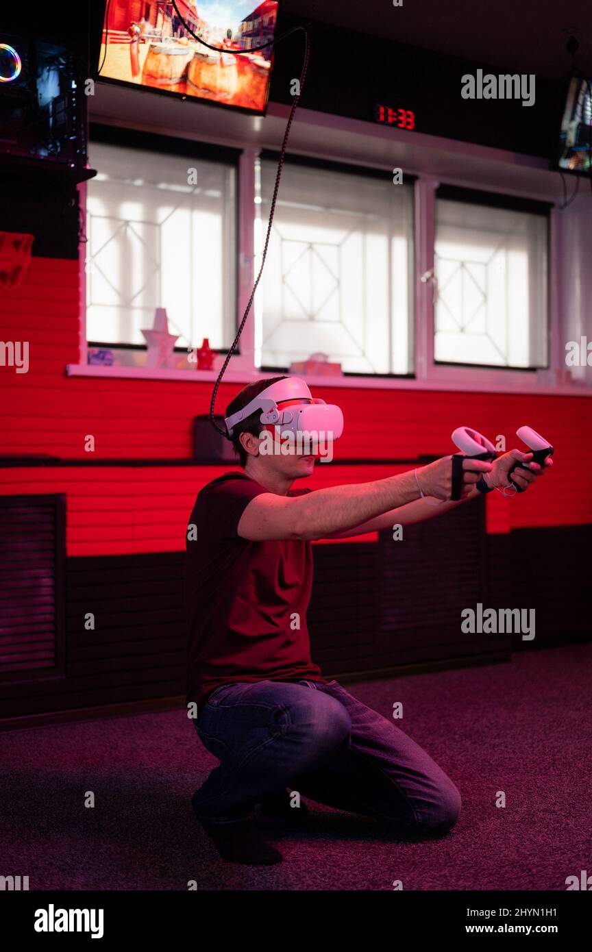 vr game and virtual reality. man gamer fun playing on futuristic simulation video shooting game holding in hands joysticks gun in entertainment vr roo Stock Photo