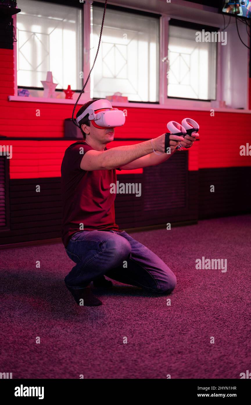 vr game and virtual reality. man gamer fun playing on futuristic simulation video shooting game holding in hands joysticks gun in entertainment vr roo Stock Photo