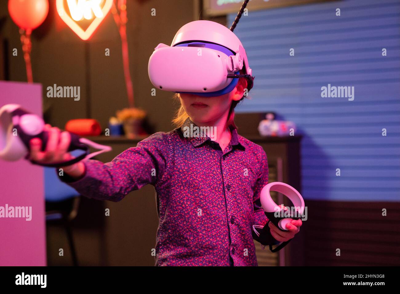 vr game and virtual reality. kid boy gamer six years old fun playing on futuristic simulation video game in 3d glasses and joysticks in entertainment Stock Photo