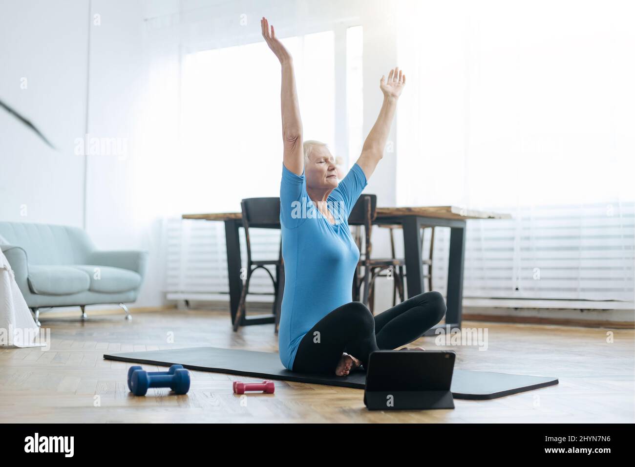 elderly woman sitting in a yoga pose in front of an open laptop Stock ...