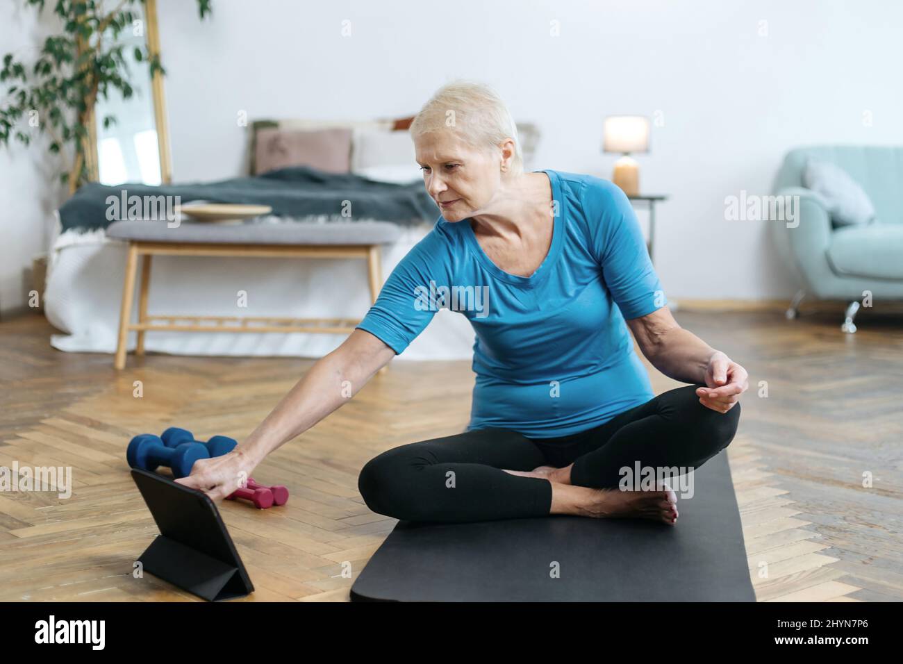 elderly woman sitting in a yoga pose in front of an open laptop Stock ...