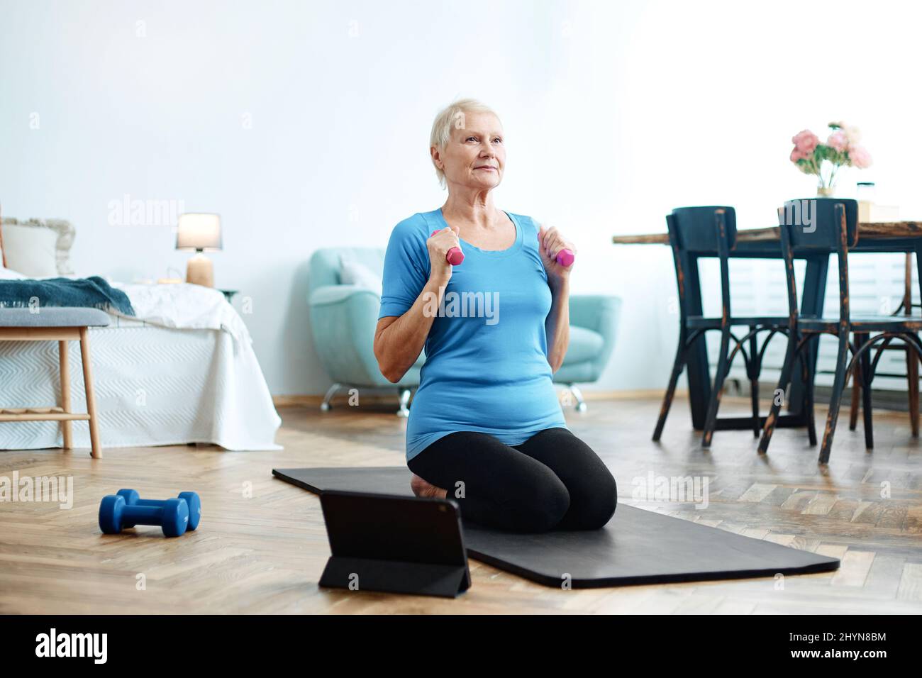 elderly woman sitting in a yoga pose in front of an open laptop Stock ...