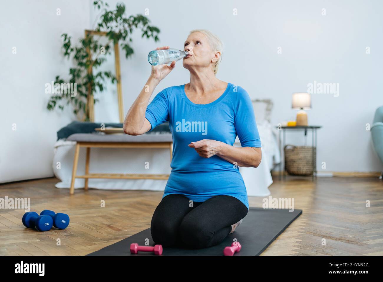 elderly woman sitting in a yoga pose in front of an open laptop Stock ...