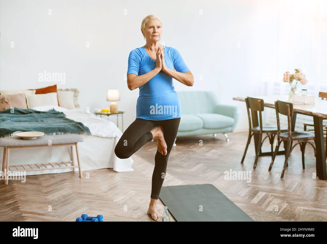 elderly woman sitting in a yoga pose in front of an open laptop Stock ...