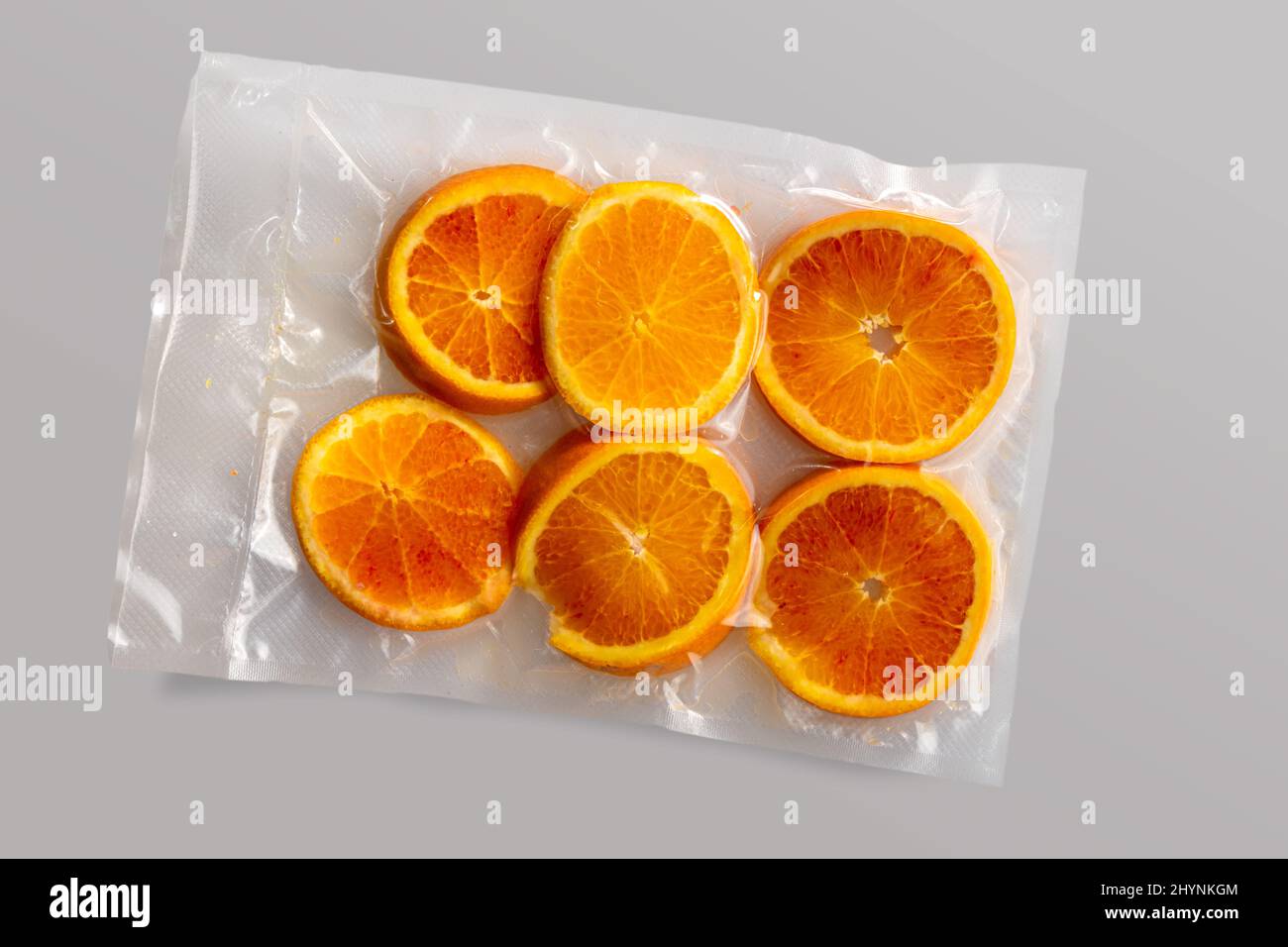 Slices of oranges fruit in vacuum packed sealed for sous vide cooking isolated on Grey background in top view Stock Photo