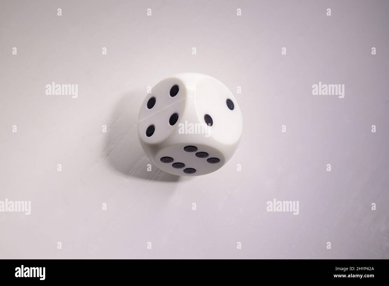 Details of gambling cube on white wooden table, it is not clear what will be the result. Stock Photo