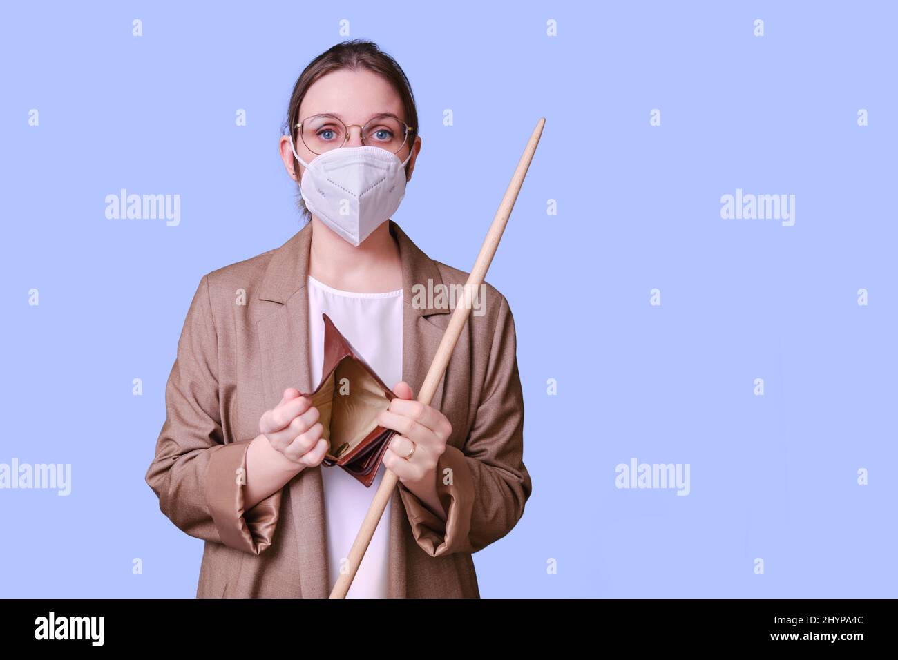 Woman teacher in medical face mask holding empty wallet on studio ...