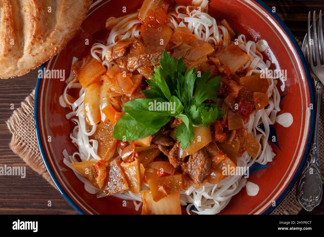 Hot Uighur dish served with herbs and flatbread. Stock Photo
