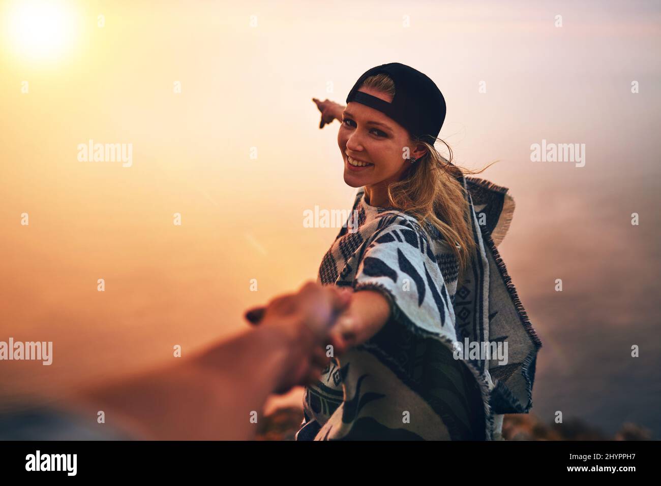 Lets go see whats over there. Portrait of a happy young hiker pointing out a foggy view while holing her boyfriends hand. Stock Photo