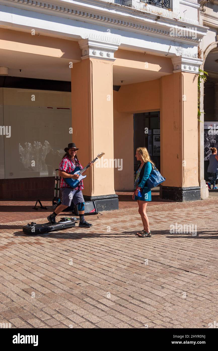 A warm autumn day during Covid in Ipswich Town Centre  a busker performs and a woman dances to the music in the Cornhillt Square, Suffolk, UK Stock Photo