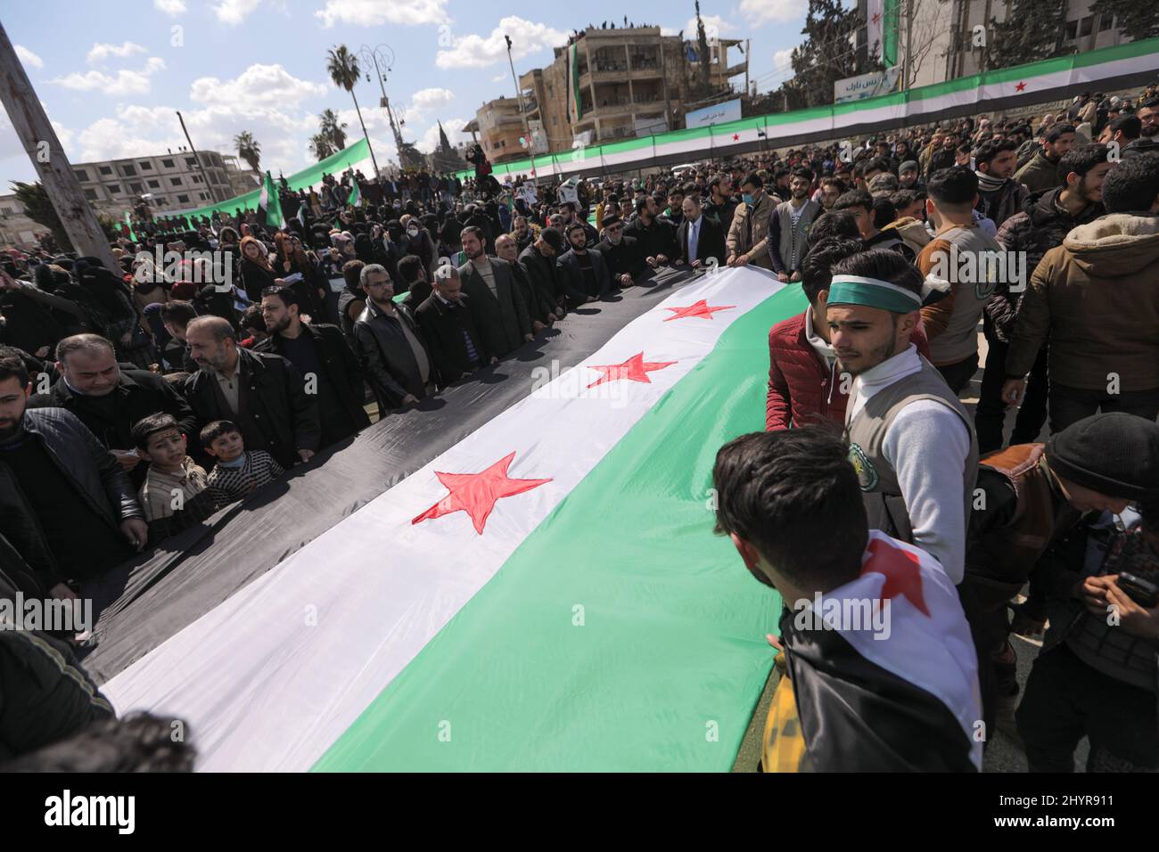 People hold an opposition flag during a protest marking the 11th anniversary of the start of the Syrian conflict, in the opposition-held Idlib, Syria March 15, 2022. REUTERS/Khalil Ashawi Stock Photo