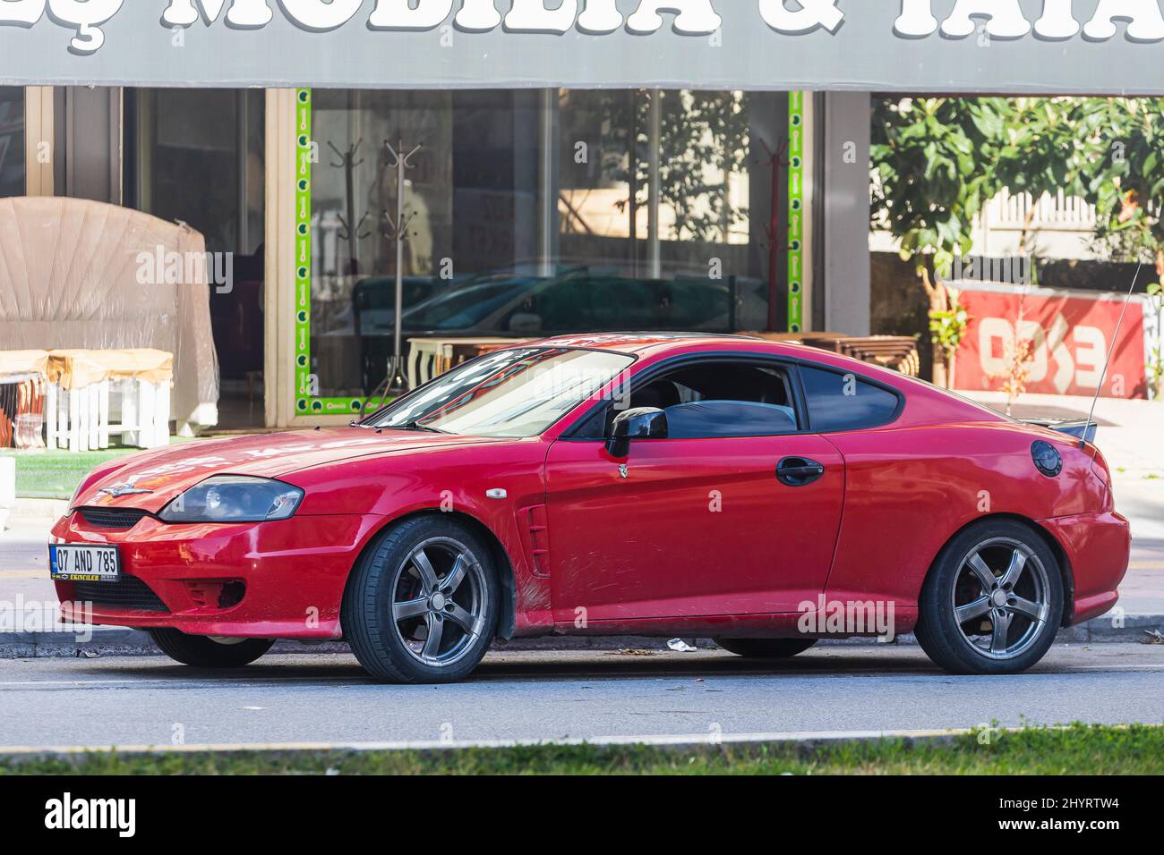 Side; Turkey – March 05 2022:  red Hyundai Tiburon  is parked  on the street on a warm day against the backdrop of a buildung,   shop Stock Photo